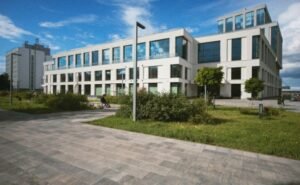 Façade vitrée de bureaux modernes avec aménagement extérieur, idéal pour une Agence immobilière.