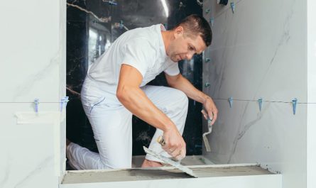 Pose de colle à carrelage par un expert pour refaire salle de bain avec du marbre blanc et noir.