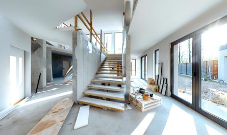 Intérieur d'une maison de style moderne en cours de rénovation avec des escaliers en marbre et du béton apparent.
